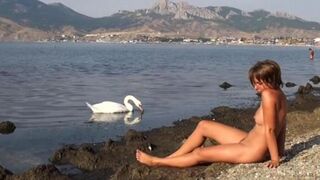 A hot naked chick is having fun on the riverbank, capturing every moment