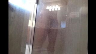 A guy washes his body under the shower with a camera