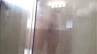 A guy washes his body under the shower with a camera