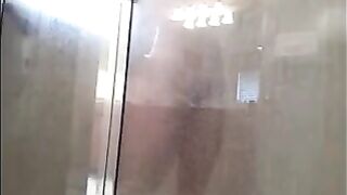 A guy washes his body under the shower with a camera