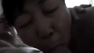 An adult Chinese woman practices her blowjob skills on him