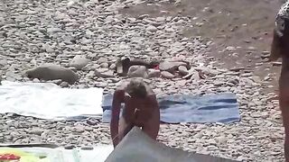 A couple of nudists enjoy each other on the beach