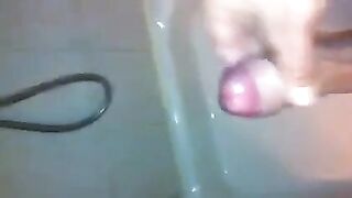 The kid masturbates his dick under the shower jet