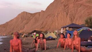 A group of girls are playing volleyball naked on the beach