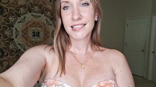 A woman massages her breasts with shimmering oil, showcasing a sensual JOI performance